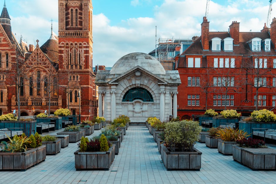 A rooftop terrace in Camden Town NW1 featuring a paved pathway leading towards a small classical pavilion with a domed roof and arched opening. The terrace is decorated with numerous rectangular woode